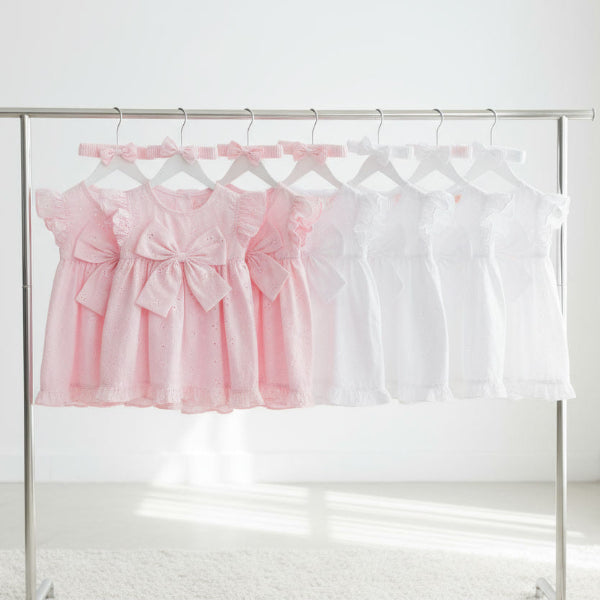 Pink and white dresses on a rack against a white background