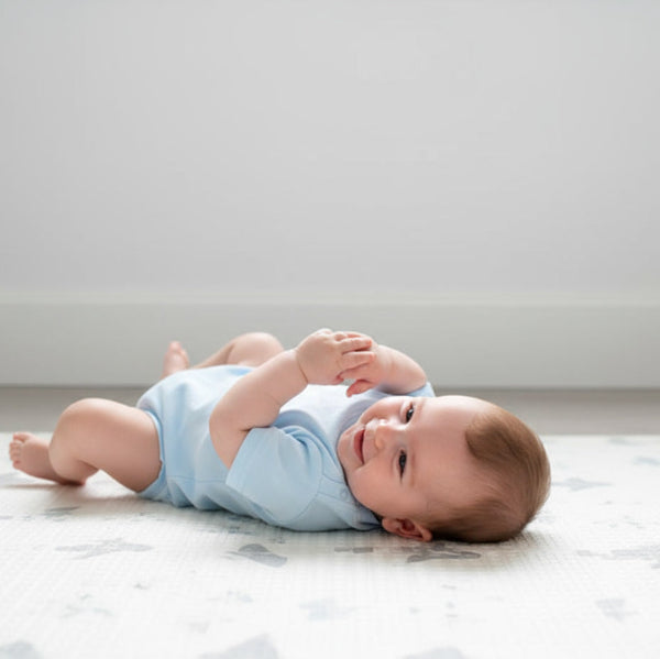 Baby lying on a light-colored floor with a plain background