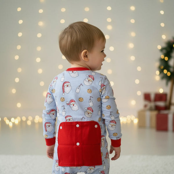 Child wearing a festive outfit with Santa Claus pattern in a softly lit room.
